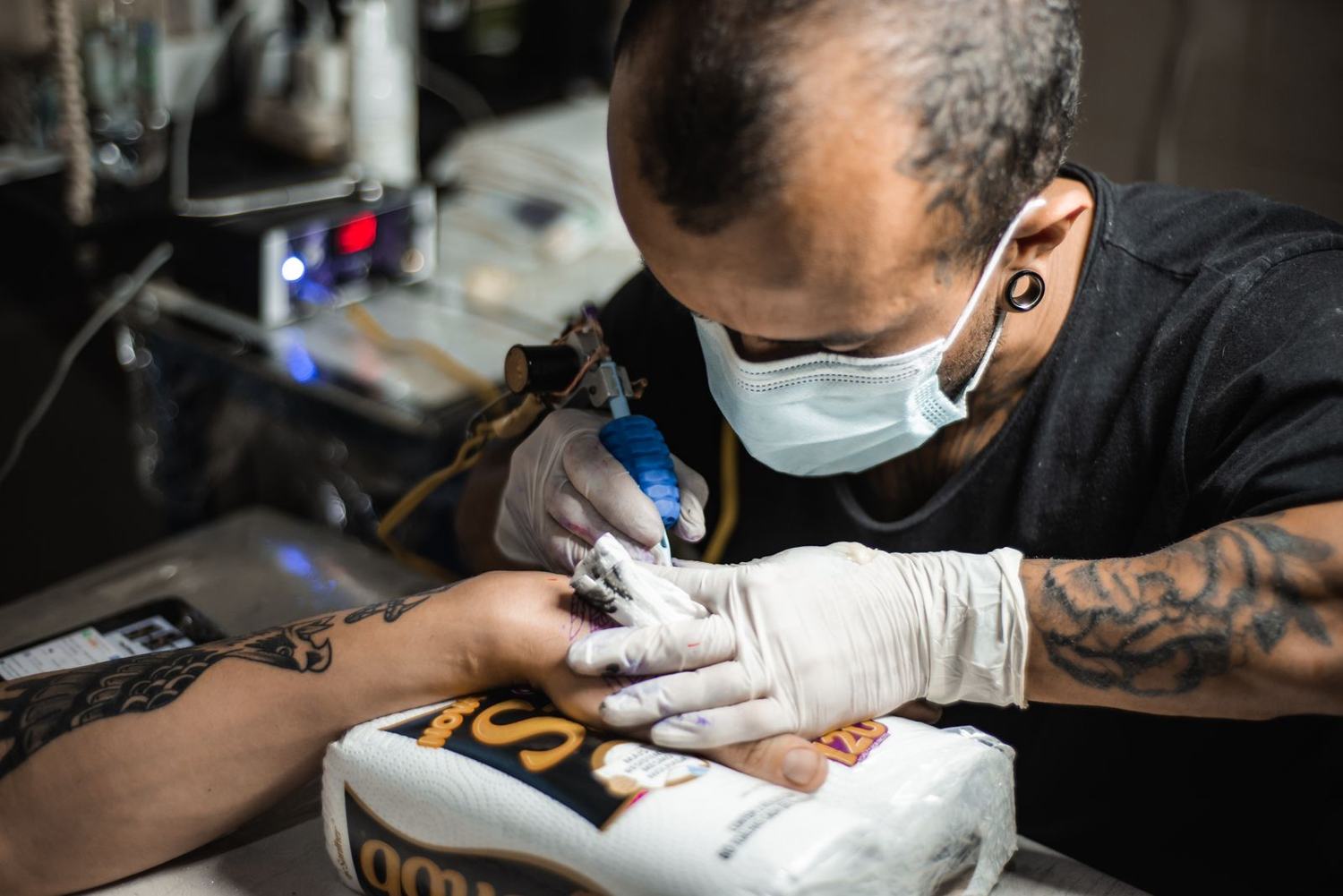 Tatuador de máscara trabalhando
