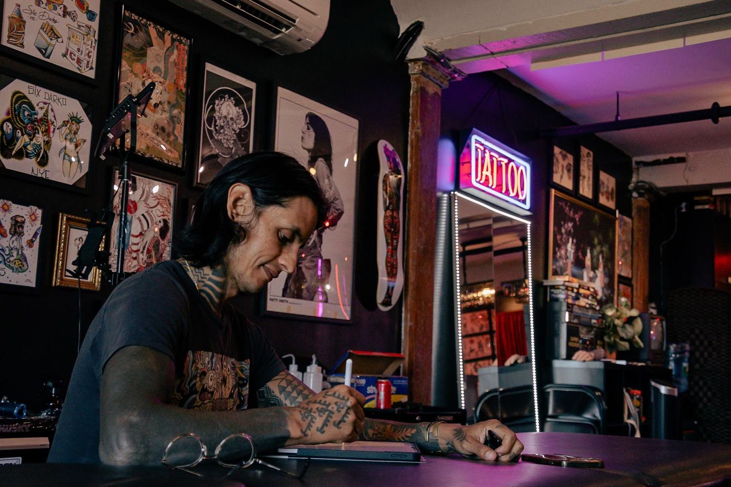 Tatuador trabalhando em estúdio de tatuagem com iluminação neon